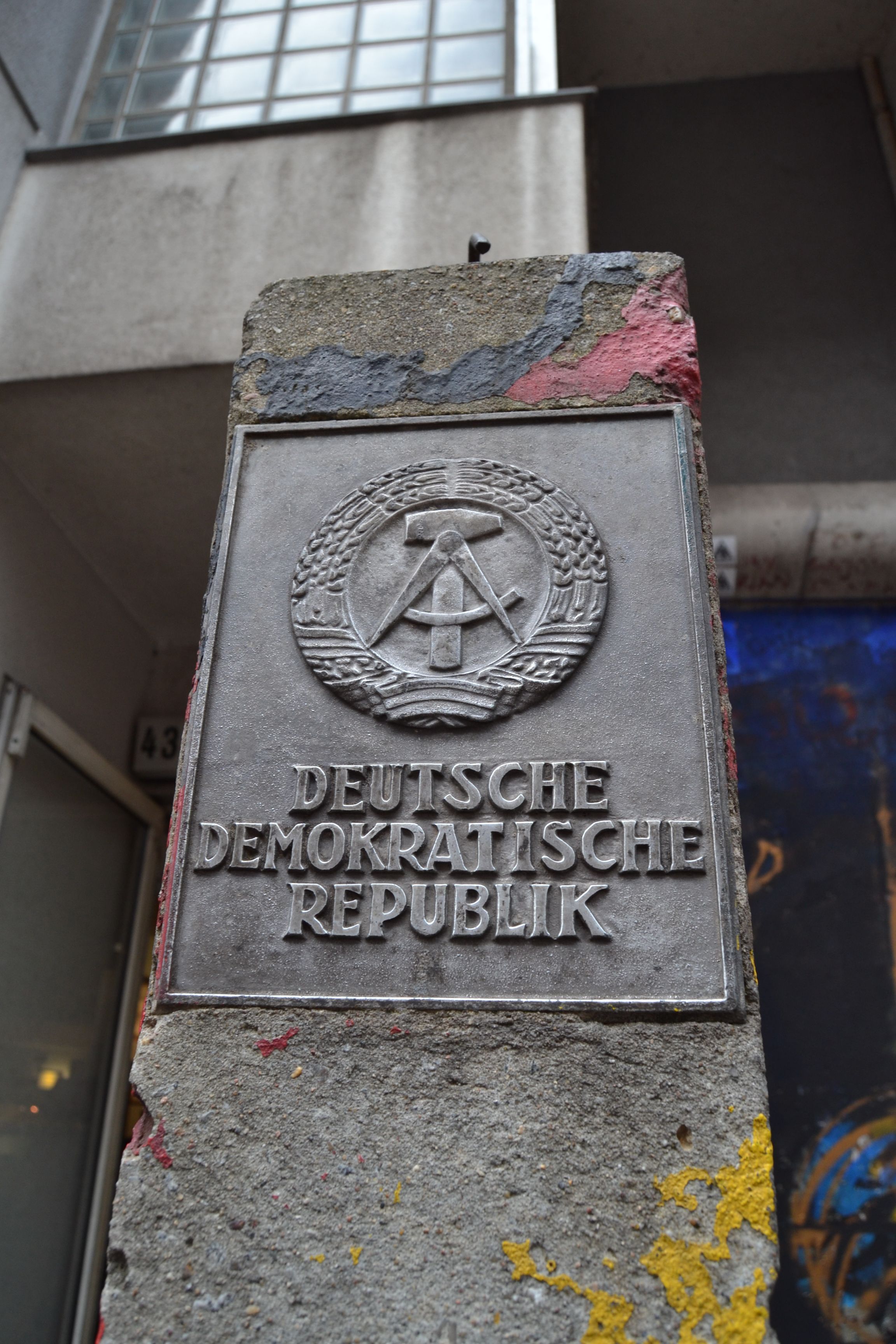 metal plate on a concrete pillar that has the German Democratic Repulic's hammer and compass